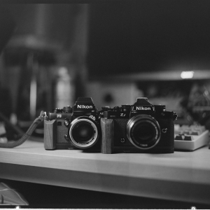 Two cameras sitting on a desk in black and white