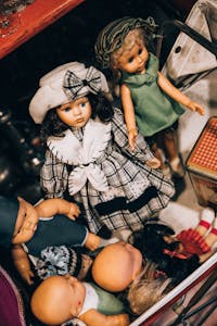 A collection of various vintage dolls arranged in an open drawer with nostalgic charm.